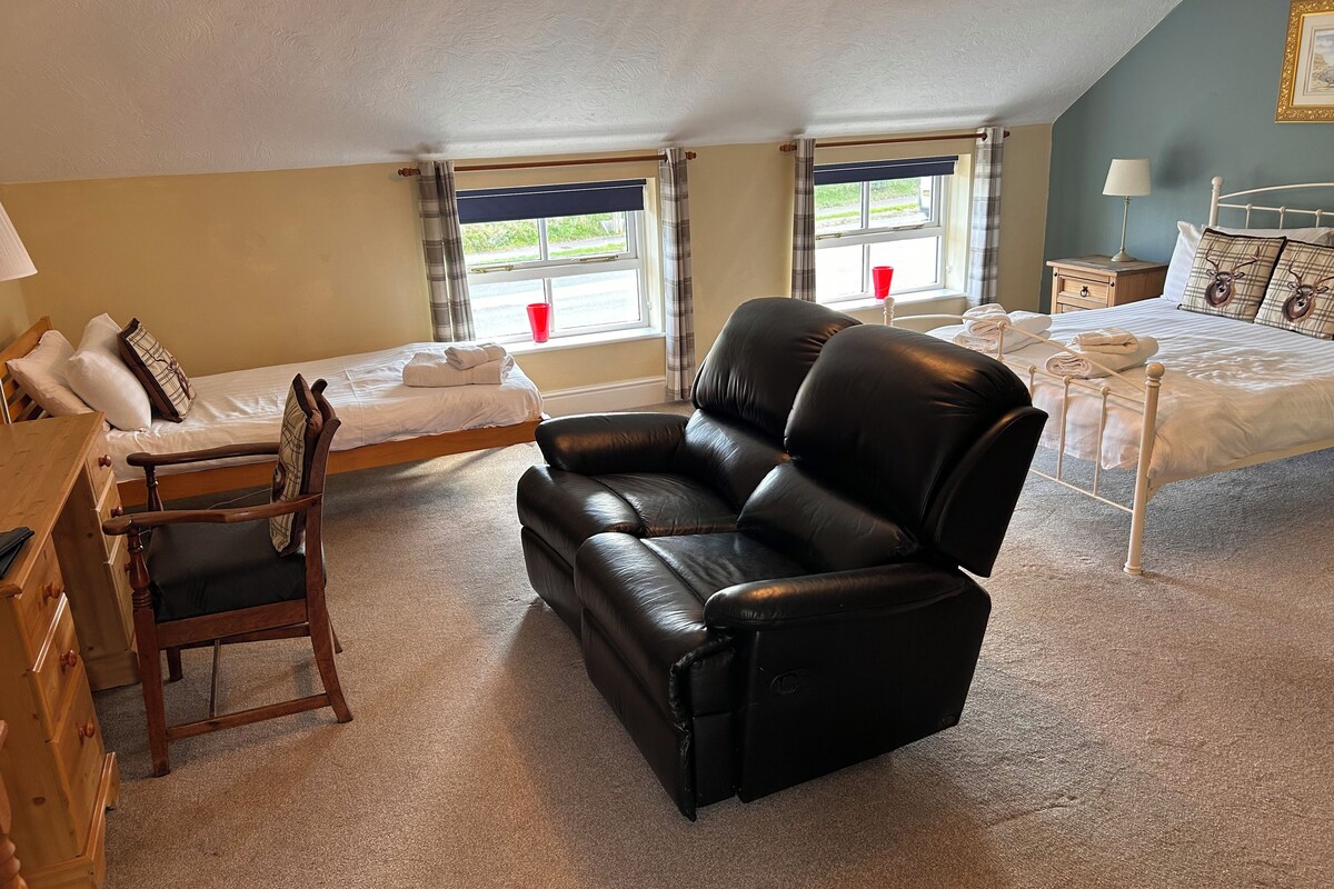 A room with a bed, a sofa, a desk, and a window with curtains.