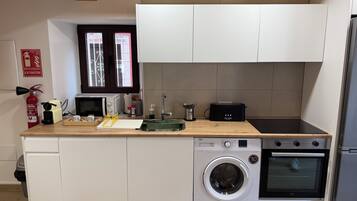 Eine kleine Küche mit Waschmaschine, Backofen, Mikrowelle und Toaster.