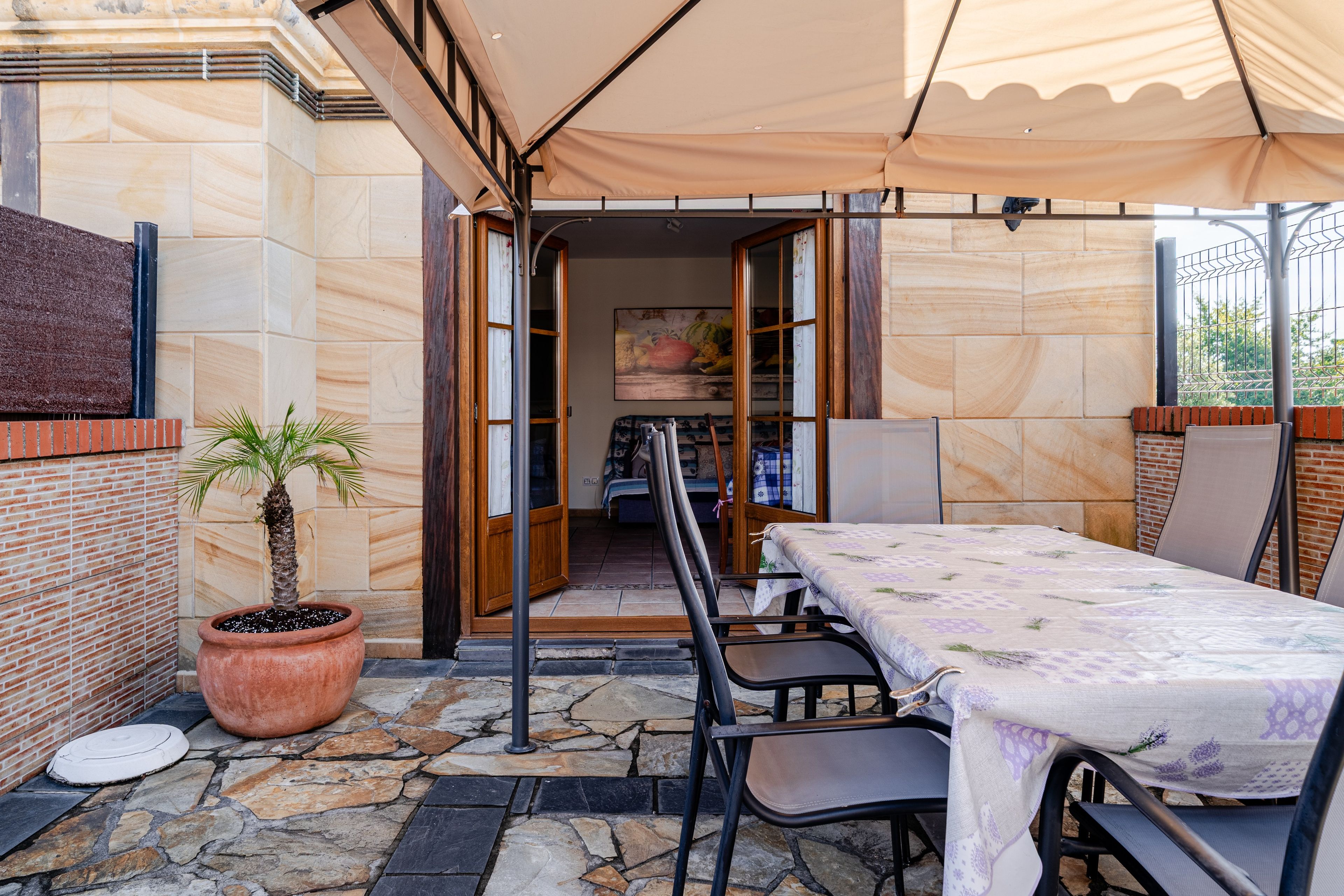A patio area with a table and chairs, a potted plant, and a view into the interior through a doorway.