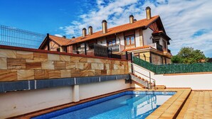 Ein Swimmingpool mit einer Steinmauer und einer Treppe, die zu einem Haus mit einem Ziegeldach führt.