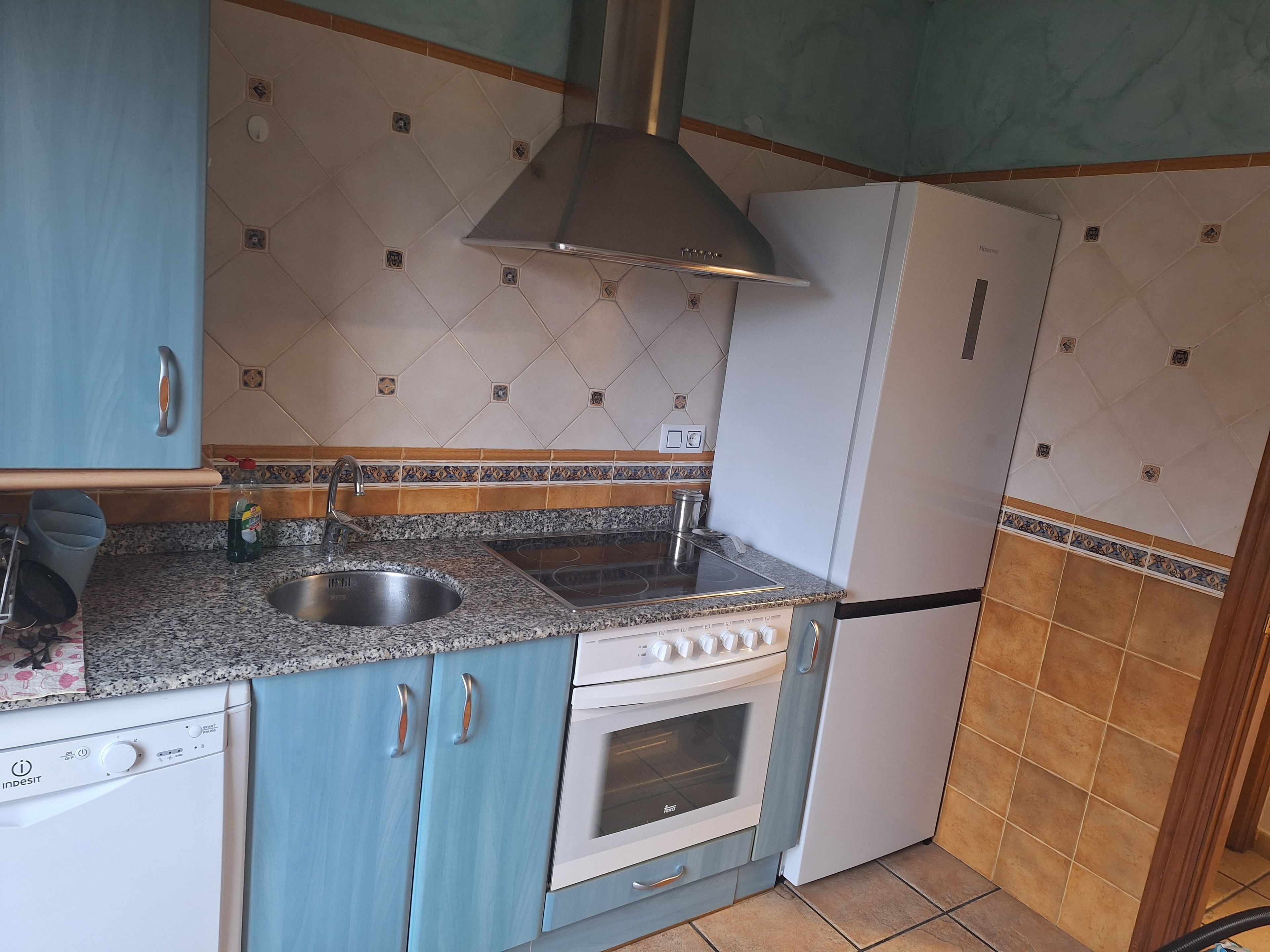 Een kleine keuken met een spoelbak, fornuis, oven en vaatwasser.