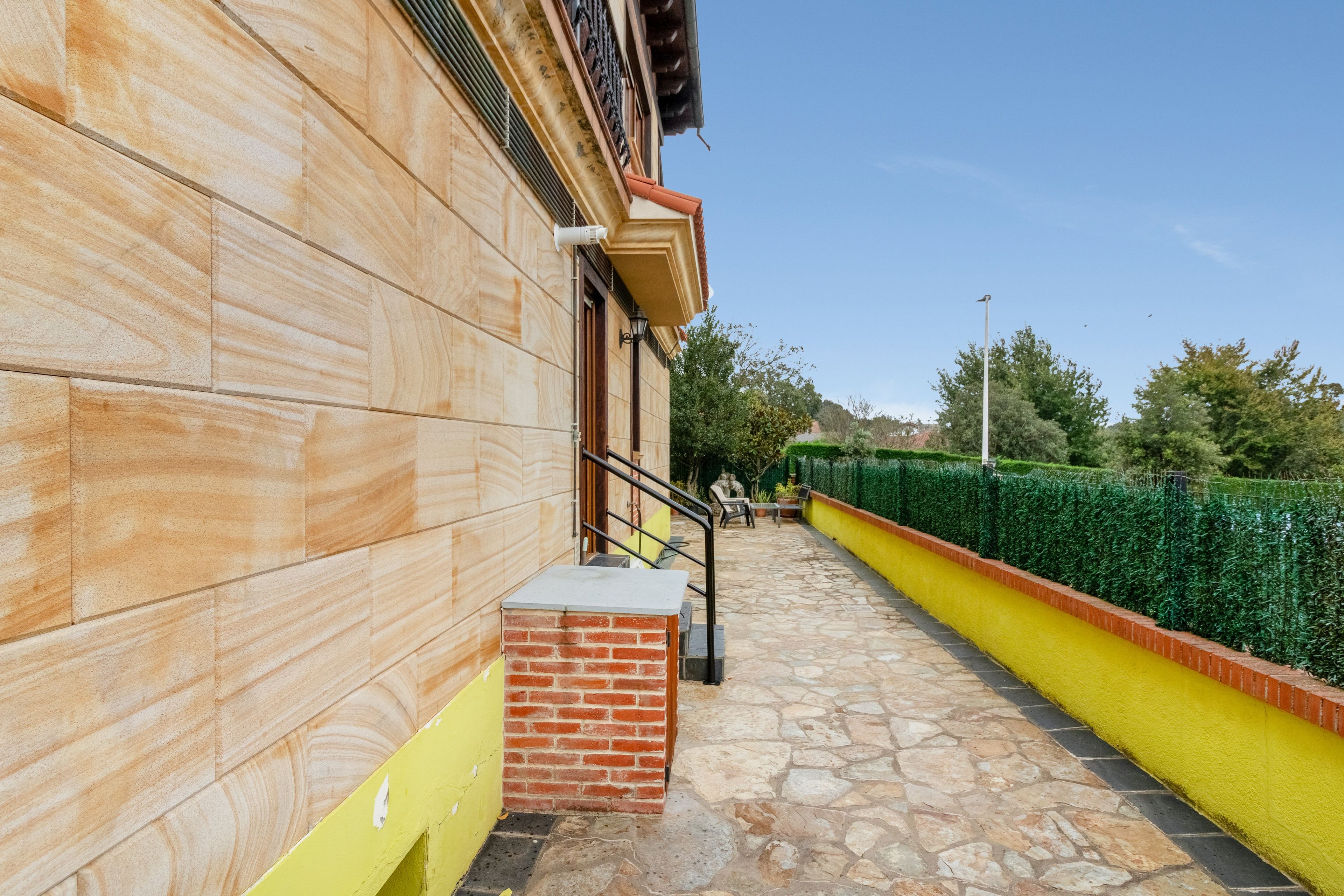 A building with a stone facade, a brick entrance, and a yellow and green wall.