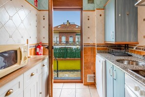 A kitchen with white cabinets, a microwave, a sink, and a fire extinguisher.