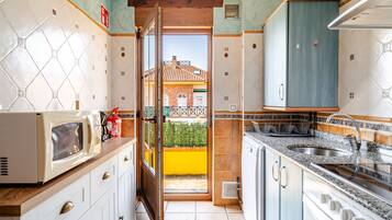 A kitchen with a view to the outside, featuring a microwave, stove, sink, and cabinets.