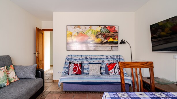 Ein Zimmer mit einem Bett, einem Schlafsofa, einem Gemälde, einer Lampe und einem Fernseher.
