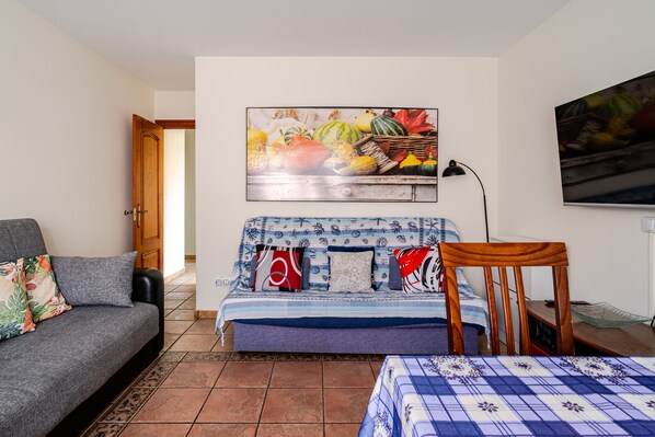 Een kamer met een bed, een slaapbank, een schilderij, een lamp en een televisie.