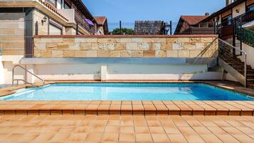 Ein Swimmingpool mit Steinmauer und gefliestem Deck, umgeben von Gebäuden mit Balkonen.