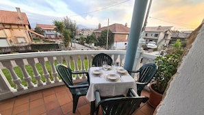 Una terraza con mesa lista para cuatro personas, rodeada de sillas y vista al barrio.