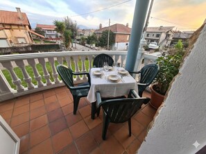 Una terraza con mesa lista para cuatro personas, rodeada de sillas y vista al barrio.