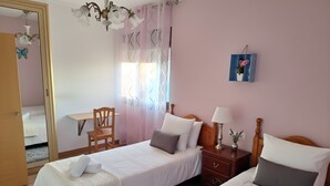 Un dormitorio con dos camas, un escritorio, una silla, una mesita de noche y una araña.