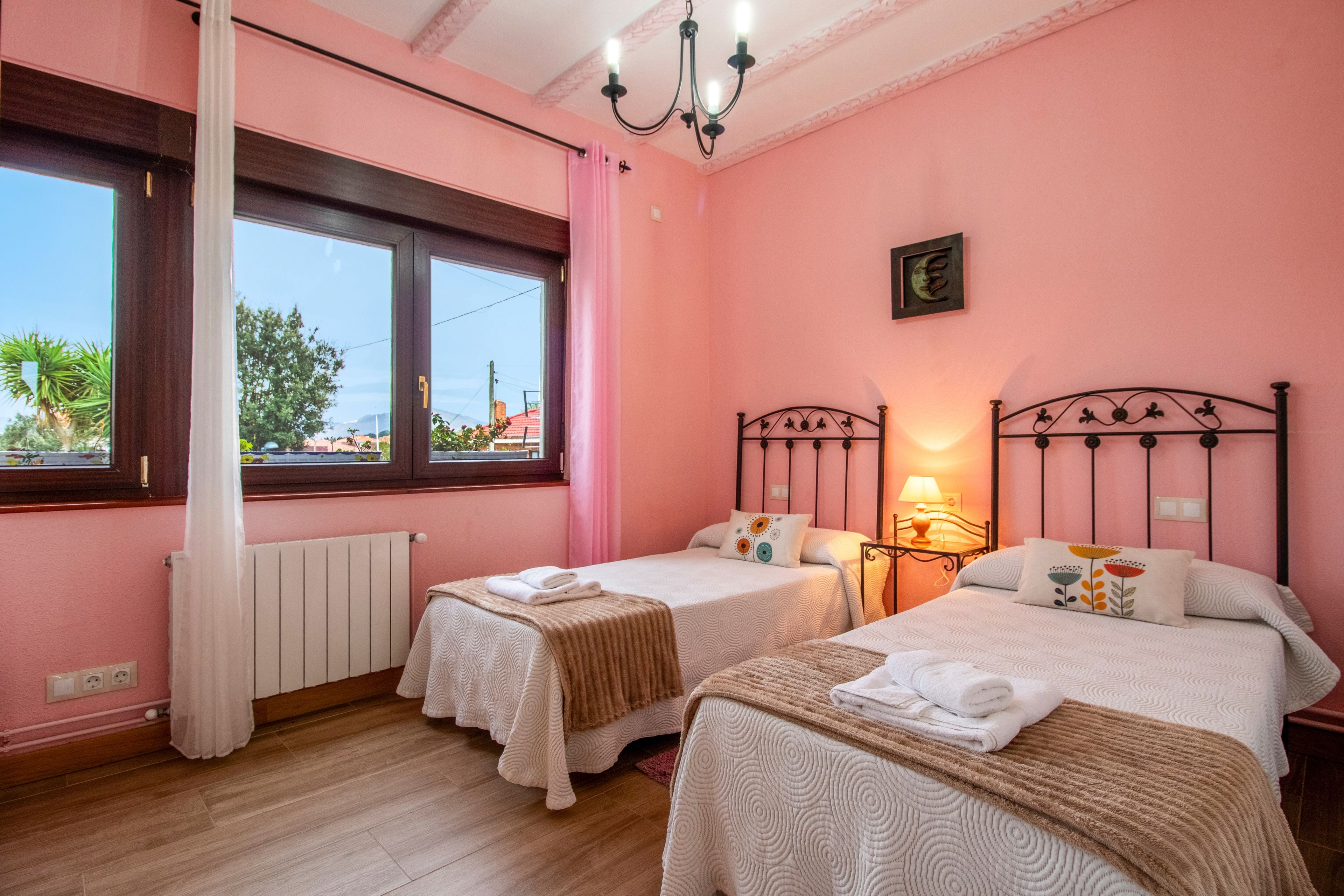 Une chambre avec deux lits, une fenêtre, un radiateur et un lustre.