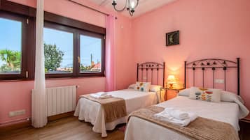 Une chambre avec deux lits, une fenêtre, un radiateur et un lustre.
