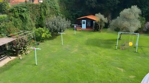 A grassy yard with a small house, a swing set, and a clothesline.
