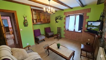 A living room with a television, wooden furniture, and a green wall.