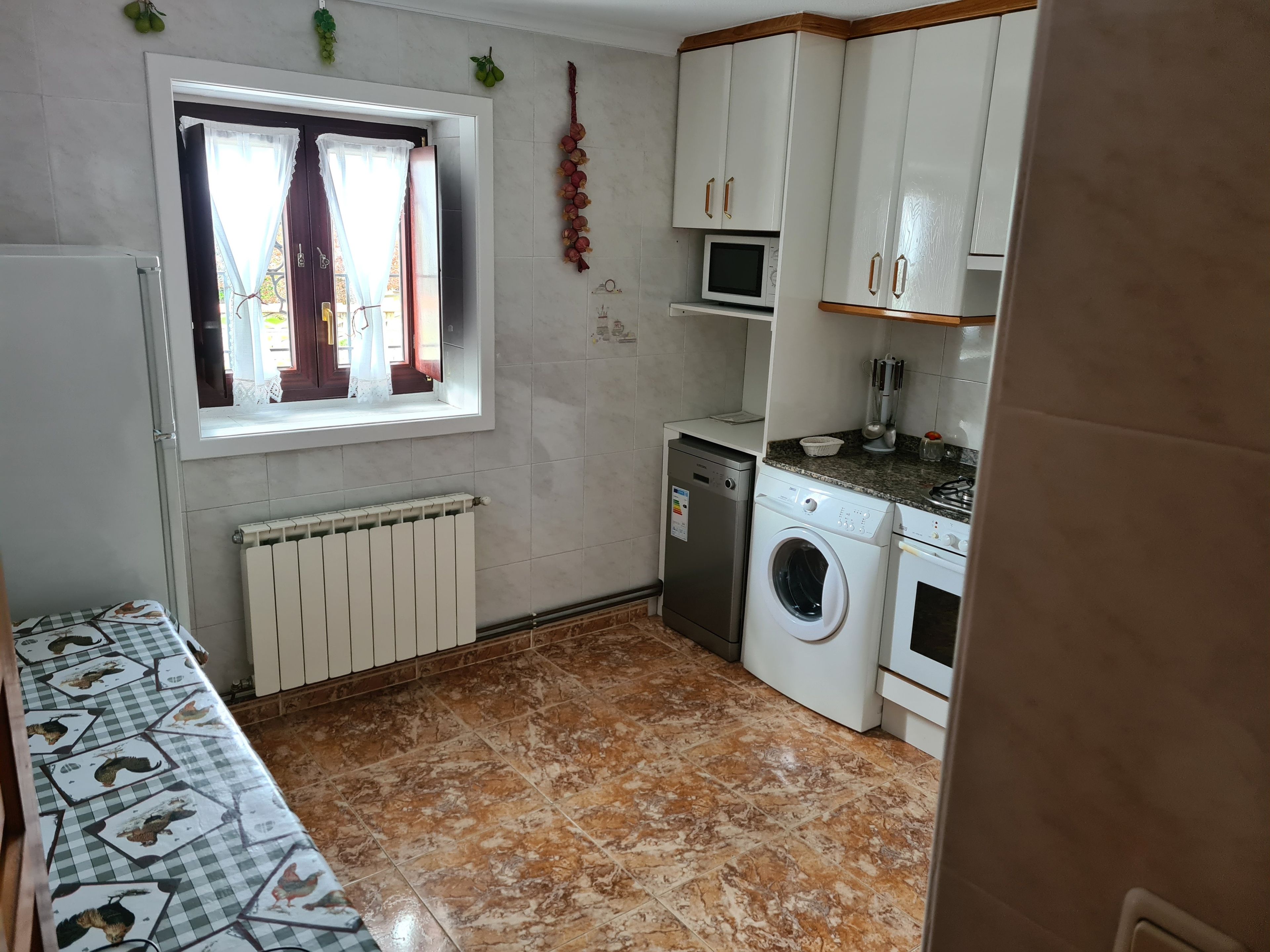 A compact kitchen with a washing machine, a microwave, and a small countertop.