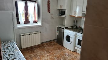 A compact kitchen with a washing machine, a microwave, and a small countertop.