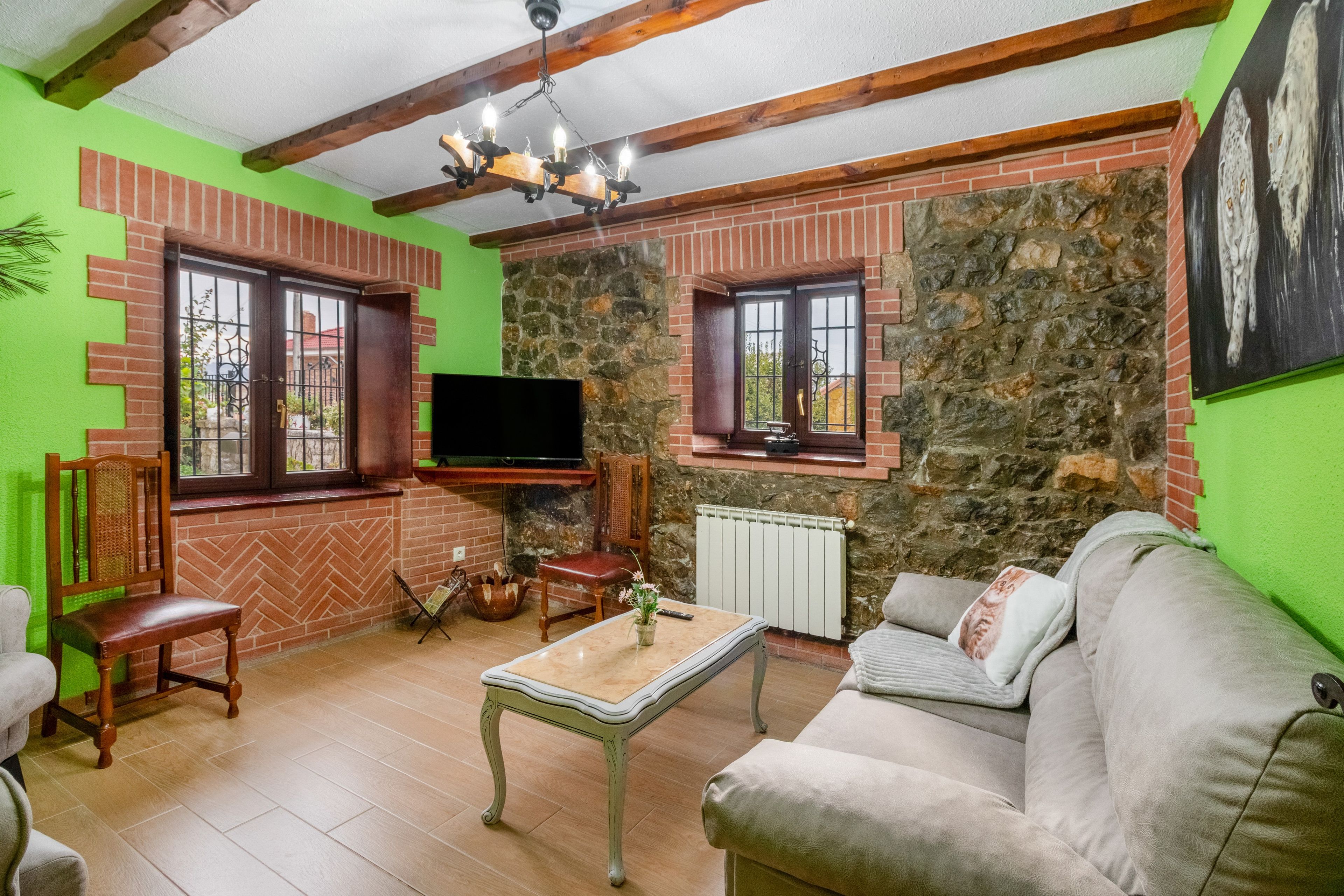 Een woonkamer met een stenen muur, een televisie, een bank en een salontafel.