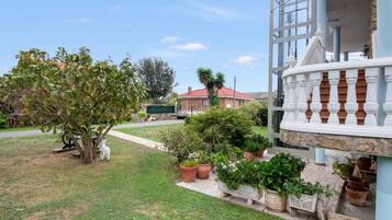 A residential property with a well-maintained lawn, potted plants, and a white decorative fence.