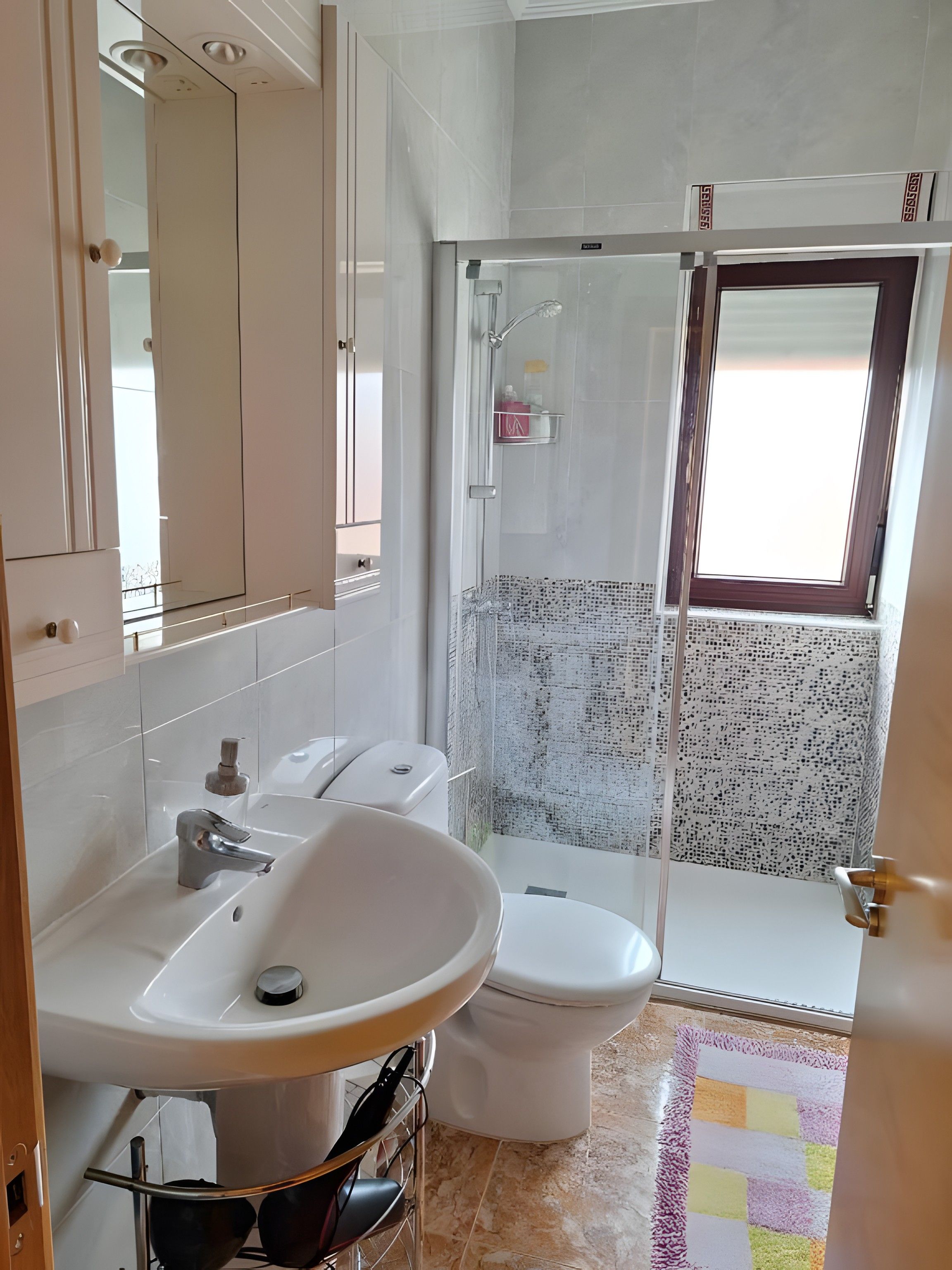 Baño con lavamanos blanco, inodoro y ducha.