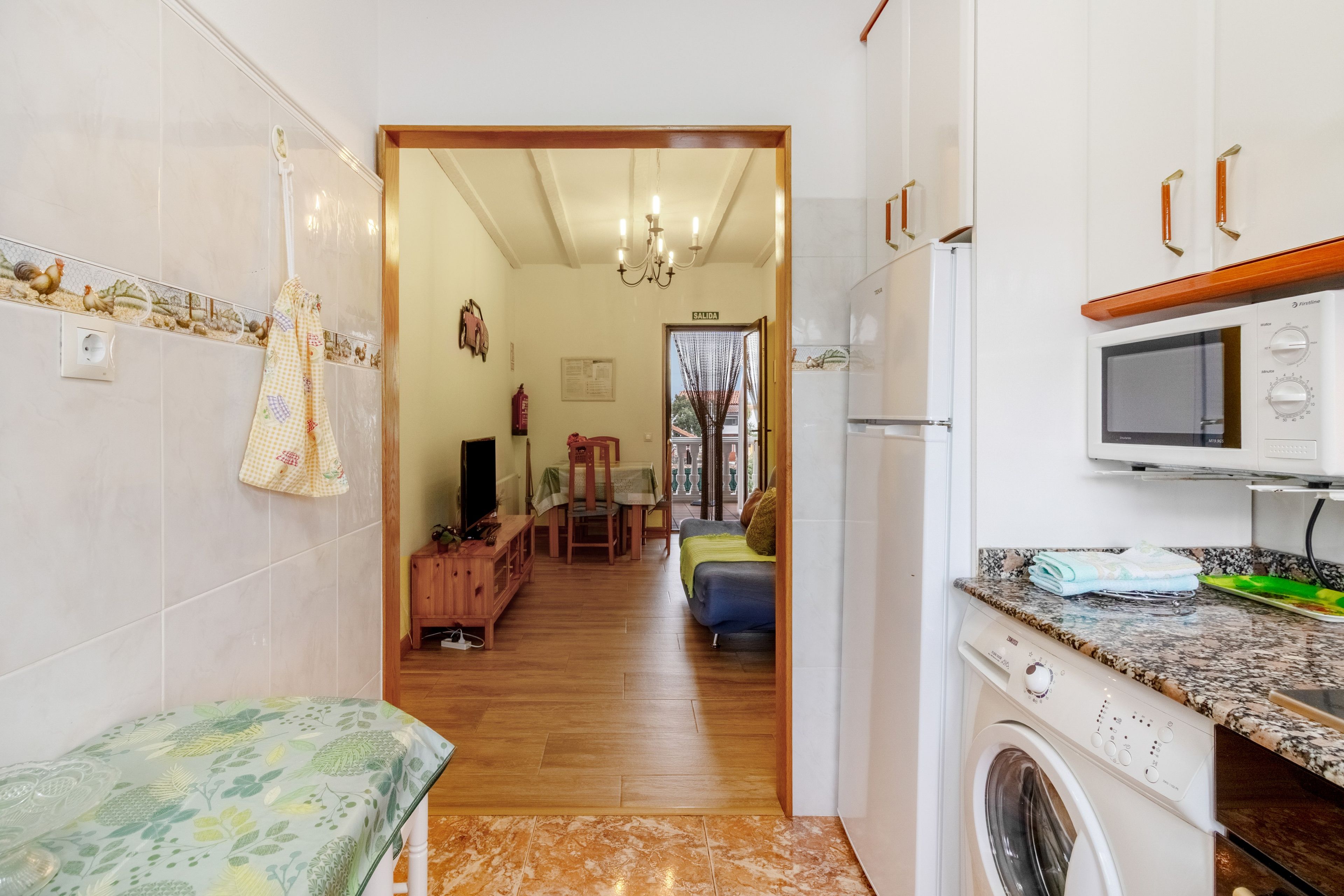 A compact kitchen with a washing machine, a microwave, and a dining area with a table and chairs.