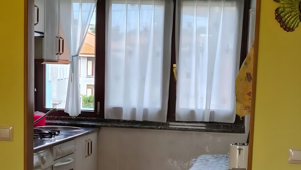 Eine Küche mit Waschmaschine, einem Esstisch mit Stühlen und einem Fenster mit Vorhängen.