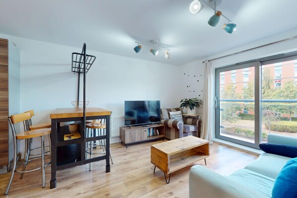 Een moderne woonkamer met een eetgedeelte, een televisie en een groot raam.