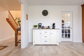 A room with a white cabinet, a clock on the wall, and a door leading outside. - White Horse Overlook | Lancaster | Amish Country (Gap)