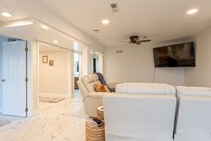 A modern living room with a sectional sofa, a ceiling fan, and a flat-screen TV mounted on the wall. - White Horse Overlook | Lancaster | Amish Country (Gap)