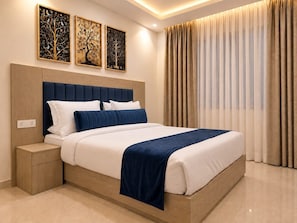 A modern hotel room with a large bed, a wooden headboard, and a nightstand. There are three framed artworks on the wall above the bed. - The Beetles Delhi Airport (New Delhi)