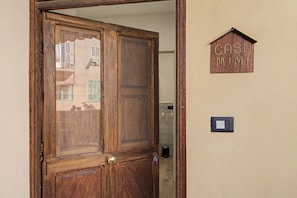 A wooden door with a brass handle and a keyhole, a small mailbox on the wall, and a light switch.