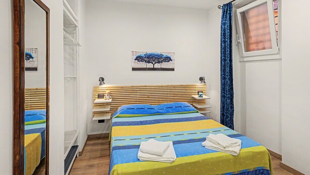 A bedroom with a bed, bedside tables, a mirror, a window with curtains, and a wall-mounted picture. - Apartment 'Mimi' with Balcony, Wi-Fi and Air Conditioning (Taggia)