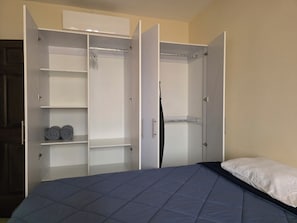 A bedroom with a bed, a wardrobe with multiple shelves, and a door. - 4BR Gated Oasis for Families & Pets – 15 Min to El Tunco Surf and Sunset Park. (Zaragoza)