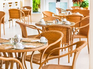 A series of wicker tables with chairs, each set with white cups and saucers, suggesting a dining or tea area. - Sunbay- Breakfast, hotel, WiFi, Beach Access (Bridgetown)