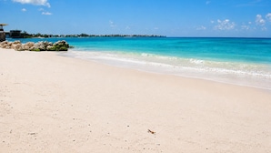 A beach with clear turquoise water, a sandy shore, and a distant shoreline with buildings. - Sunbay- Breakfast, hotel, WiFi, Beach Access (Bridgetown)