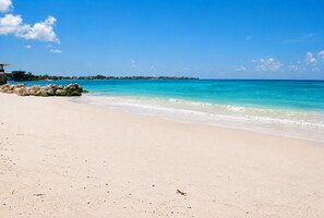 A beach with clear turquoise water, a sandy shore, and a distant shoreline with buildings. - Sunbay- Breakfast, hotel, WiFi, Beach Access (Bridgetown)