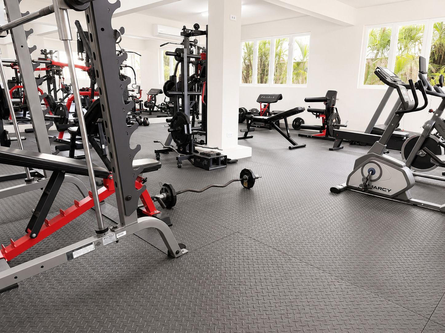Un gimnasio con varios equipos de ejercicio, como una estructura para sentadillas, una prensa de banca y cintas de correr.