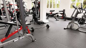 Un gimnasio con varios equipos de ejercicio, como una estructura para sentadillas, una prensa de banca y cintas de correr.
