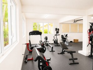 A gym with various exercise equipment, large windows, and a view of greenery outside. - Sunbay- Breakfast, hotel, WiFi, Beach Access (Bridgetown)