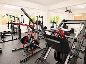 Une salle de sport équipée de divers appareils d’entraînement, notamment un support à squats, un banc de développé couché et des poids.