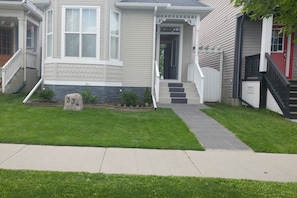 A two-story house with a front porch, a stone number plaque, and a well-maintained lawn.