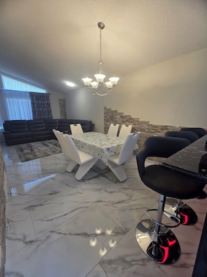 A dining area with a marble floor, a chandelier, and a dining table with chairs.