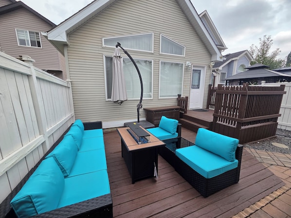 A deck with outdoor furniture, including a sofa and a table, and a pergola with a canopy.