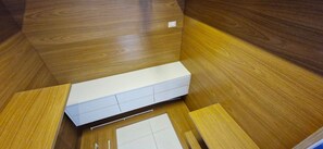 A room with wooden flooring, a white cabinet, and a small white table. - COARM0113 - Cond The Place Beach Aparts (Salvador)