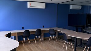 A conference room with a long table, black chairs, and an air conditioning unit on the wall. - Feet in the sand in Carneiros - Nomar (Tamandaré)