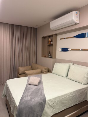 Ein Hotelzimmer mit einem Bett, einer Couch, einer Klimaanlage und einem Regal mit Dekoration.