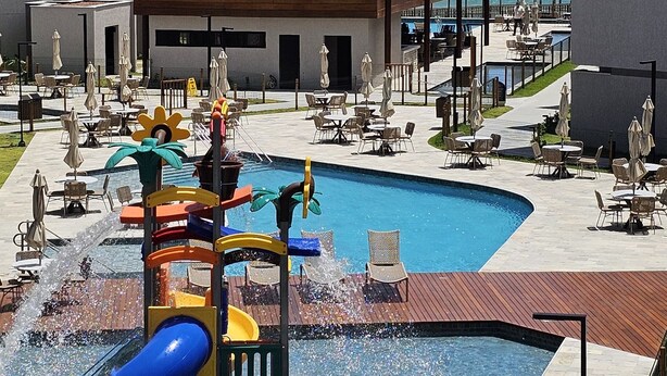 A resort pool area with a slide, lounge chairs, and a view of the ocean. - Feet in the sand in Carneiros - Nomar (Tamandaré)