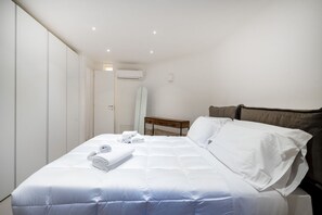 A hotel room with a bed, a bedside table, a wardrobe, and an air conditioning unit. - Borgo Principessa - Pool & Garden by the Sea (Bari)