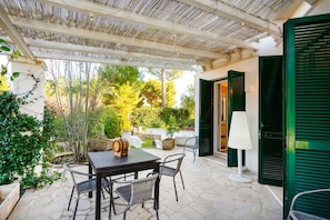 An outdoor patio with a table and chairs, a lamp, and a view of the garden. - Borgo Principessa - Pool & Garden by the Sea (Bari)