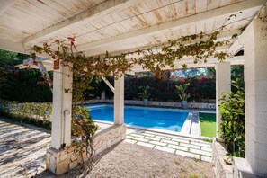 A covered outdoor area with a swimming pool, stone pillars, and greenery. - Borgo Principessa - Pool & Garden by the Sea (Bari)