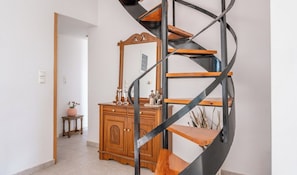A spiral staircase with a wooden finish and metal accents, leading to a room with a wooden cabinet and a mirror. - Villa Luna, Sea Views & Open Skies in Kato Assos (Kato Assos)
